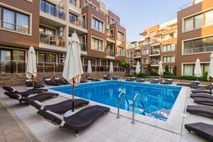 a swimming pool with chairs and umbrellas next to a building at Aпартаменти Хоризонт in Sozopol