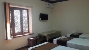 a room with two beds and a window at Muhtasham in Bukhara
