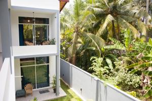 einen Balkon mit Blick auf ein Haus mit Palmen in der Unterkunft Alvas house in Hikkaduwa