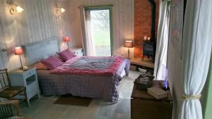 una camera da letto con un letto con cuscini rosa e una finestra di Au Pont Ricoul a Saint-Pierre-de-Plesguen