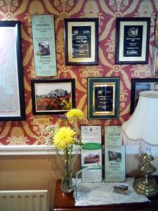 a table with a vase of flowers on a wall with pictures at Rosemount B&B in Dundalk