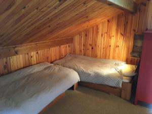 deux lits dans une chambre aux murs en bois dans l'établissement Chalet du Meilly, à Saint-Gervais-les-Bains