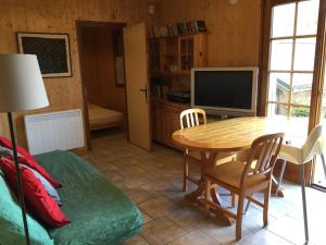un salon avec une table et une télévision dans l'établissement Chalet du Meilly, à Saint-Gervais-les-Bains