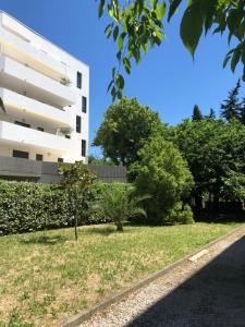 a white building with a grassy yard next to a building at Appartement Mimosa, tram 2, parking in Montpellier