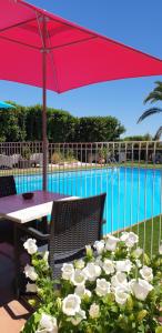 a table with a red umbrella next to a pool at Hôtel Althea - Piscine et Sauna in Béziers +30 photos