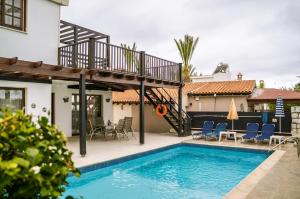 una piscina con terraza y una casa en Coralsunset Property Management Ltd, en Bahía de Coral