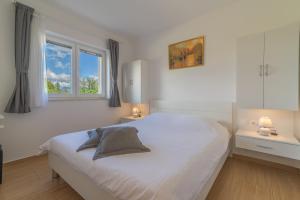 een witte slaapkamer met een bed en 2 ramen bij Apartments Enona in Nin