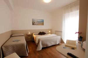 a bedroom with two beds and a desk and a window at Affittacamere da Sabri in Numana