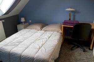 1 dormitorio con cama, escritorio y silla en chambres d'hôtes les mésanges avec salle d'eau privative pdj compris, en Kersaint-Plabennec
