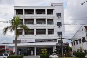 un edificio blanco con una palmera delante en Nakhone Champa Hotel, en Pakse