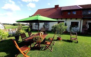 a table and chairs with a green umbrella in a yard at Komblówka in Marcinowa Wola