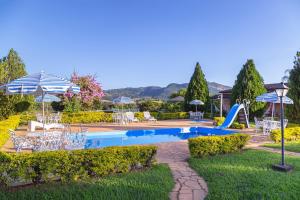 una piscina con scivolo, sedie e ombrelloni di Pousada Lua Luana a Cambuquira