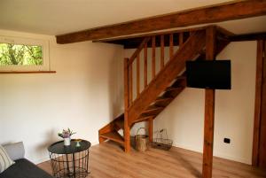 a living room with a wooden staircase with a flat screen tv at Wiosłówka - domek nad morzem in Gdańsk