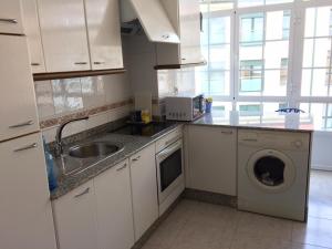 a kitchen with a sink and a washing machine at Apartamento junto al paseo marítimo de Cee in Cee