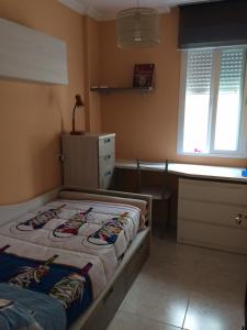 a bedroom with a bed and a desk and window at Apartamento junto al paseo marítimo de Cee in Cee