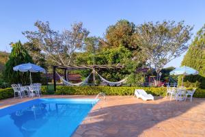 una piscina con sedie, ombrelloni e amaca di Pousada Lua Luana a Cambuquira