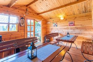 eine Holzhütte mit Bänken und Tischen in der Unterkunft Villa Konwalia in Grzybowo