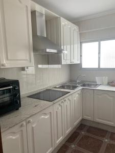 マラガにあるApartamento Angelinmaの白いキャビネット、シンク、電子レンジ付きのキッチンが備わります。