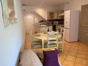 a kitchen with a table and chairs and a white refrigerator at Villa Pampasgiolu in Tizzano