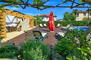 a patio with chairs and a umbrella and a pool at Apartmani Elio in Umag