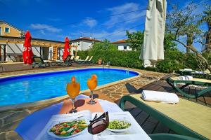 a table with plates of food next to a swimming pool at Apartmani Elio in Umag