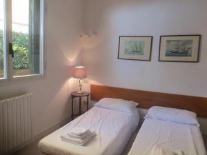 a bedroom with two beds and a lamp and a window at Appartamenti Boboli in Punta Ala