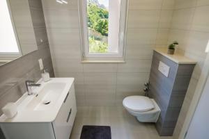 a bathroom with a toilet and a sink and a window at Apartmani Ticinovic in Omiš +37 photos
