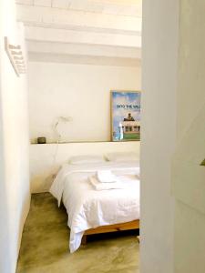 ein Schlafzimmer mit einem weißen Bett mit einem Bild an der Wand in der Unterkunft Casa Nascente - Casas de Seixe in Baiana