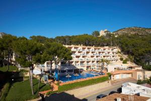 
a hotel room with a pool and a large building at Universal Aparthotel Don Camilo in Sant Elm
