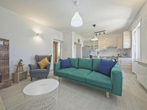 a living room with a green couch and a kitchen at Apartman Nikica in Postira