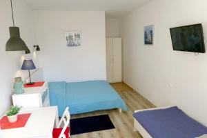 1 dormitorio con 1 cama azul y TV en Pokoje gościnne KOTWICA en Władysławowo
