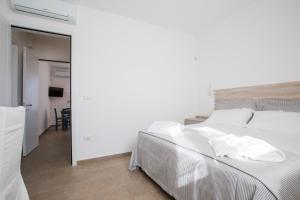 - une chambre avec un lit blanc et une salle à manger dans l'établissement Villa Milù, à Torre San Giovanni