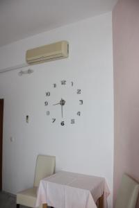 a clock on a wall with a table and chairs at Guesthouse Santor in Lastovo