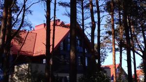 uma casa com um telhado vermelho e algumas árvores em Nidos Horizontas em Neringa
