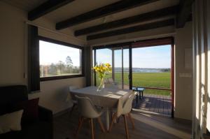 a dining room with a table and chairs and a large window at Cabanas Da Barcela in Barreiros