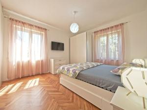 a bedroom with a bed and a television and windows at Apartman Nikica in Postira