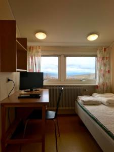 een slaapkamer met een bureau, een computer en een bed bij STF Malmfältens Folkhögskola in Kiruna