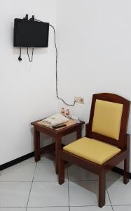 une chaise et une table avec une télévision murale dans l'établissement Hotel Bundo Permai 1, à Pacitan