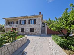 a brick house with a gate and a driveway at Apartman Nikica in Postira
