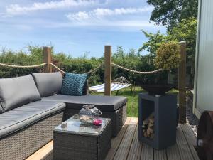 a patio with a couch and a fire place at Shepherds Hut with Hot Tub in Lymington