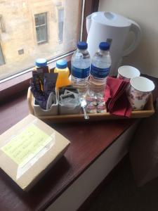 - un plateau avec des bouteilles d'eau et d'autres articles sur une table dans l'établissement Prime location rooms in high street, à Fort William