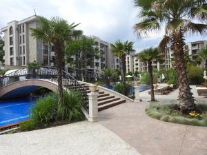 un pont sur une piscine bordée de palmiers et un bâtiment dans l'établissement Cascadas Studio, à Sunny Beach