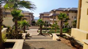 un chemin avec des palmiers devant les condos dans l'établissement Plage Des Nations Golf Resort, à Sidi Bouqnadel