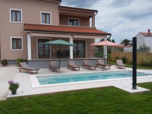 a house with a swimming pool with chairs and umbrellas at Danica in Smoljanci