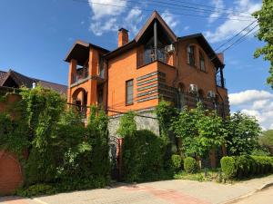 an orange brick house with bushes in front of it at Guest House Valeria in Velikiy Novgorod