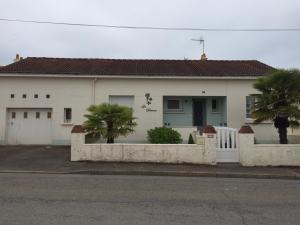 a white house with a fence and palm trees at Les Palmiers in Pornic