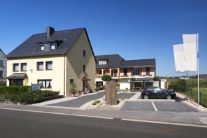 een wit huis met een auto op een oprit bij Moselweingut & Gästehaus Hubertushof in Trittenheim