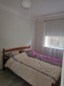 1 cama en un dormitorio con ventana en Dzīvoklis Vecpilsētā en Bauska