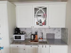 a kitchen with white cabinets and a microwave at Apartament na Morskim Wzgórzu in Mechelinki