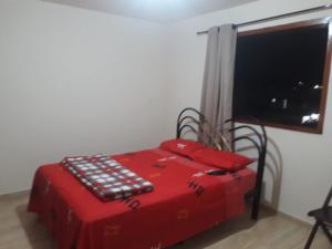 a red bed in a room with a window at kit net montanha das letras in São Thomé das Letras